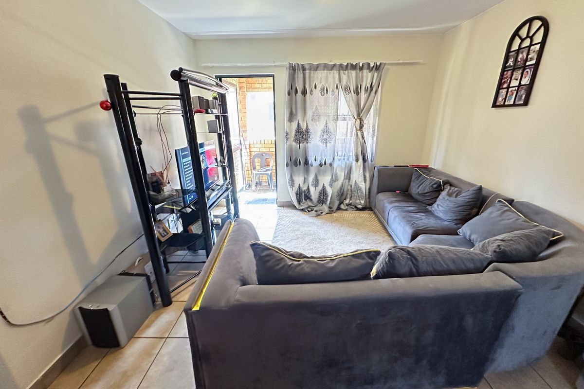 A living room featuring tiled flooring and direct access to an outdoor balcony area through a sliding door.