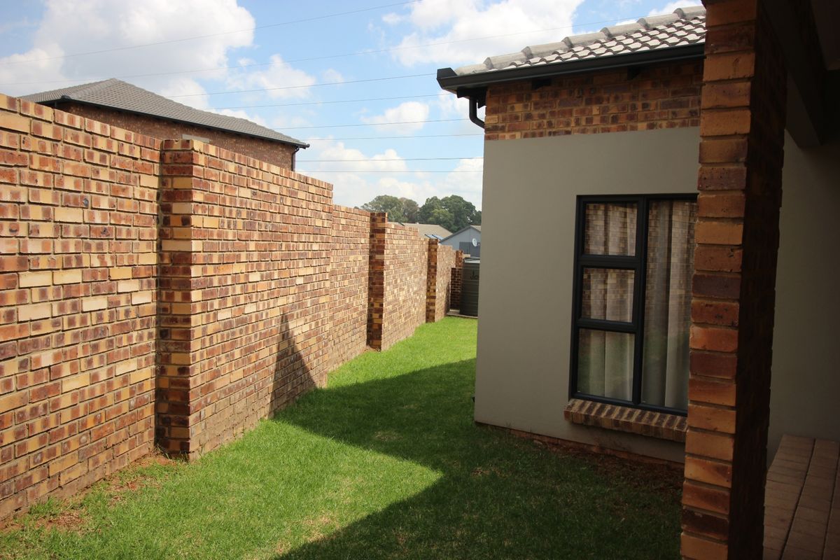 A view of the rear garden area featuring a well-maintained lawn and a solid brick boundary wall.