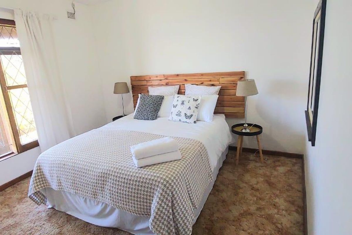 A bedroom featuring timber window frames with security burglar bars and carpeted flooring.