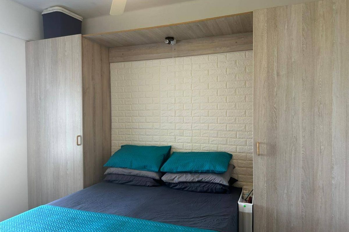 Bedroom featuring built-in light wood-grain wardrobes and a decorative faux brick feature wall with an integrated ceiling fan.