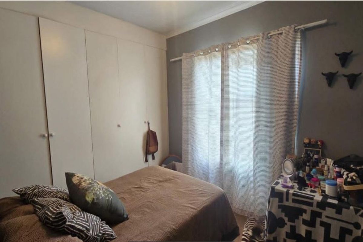 A functional bedroom featuring built-in cupboards and a window with natural light, offering a neutral base for personalization.