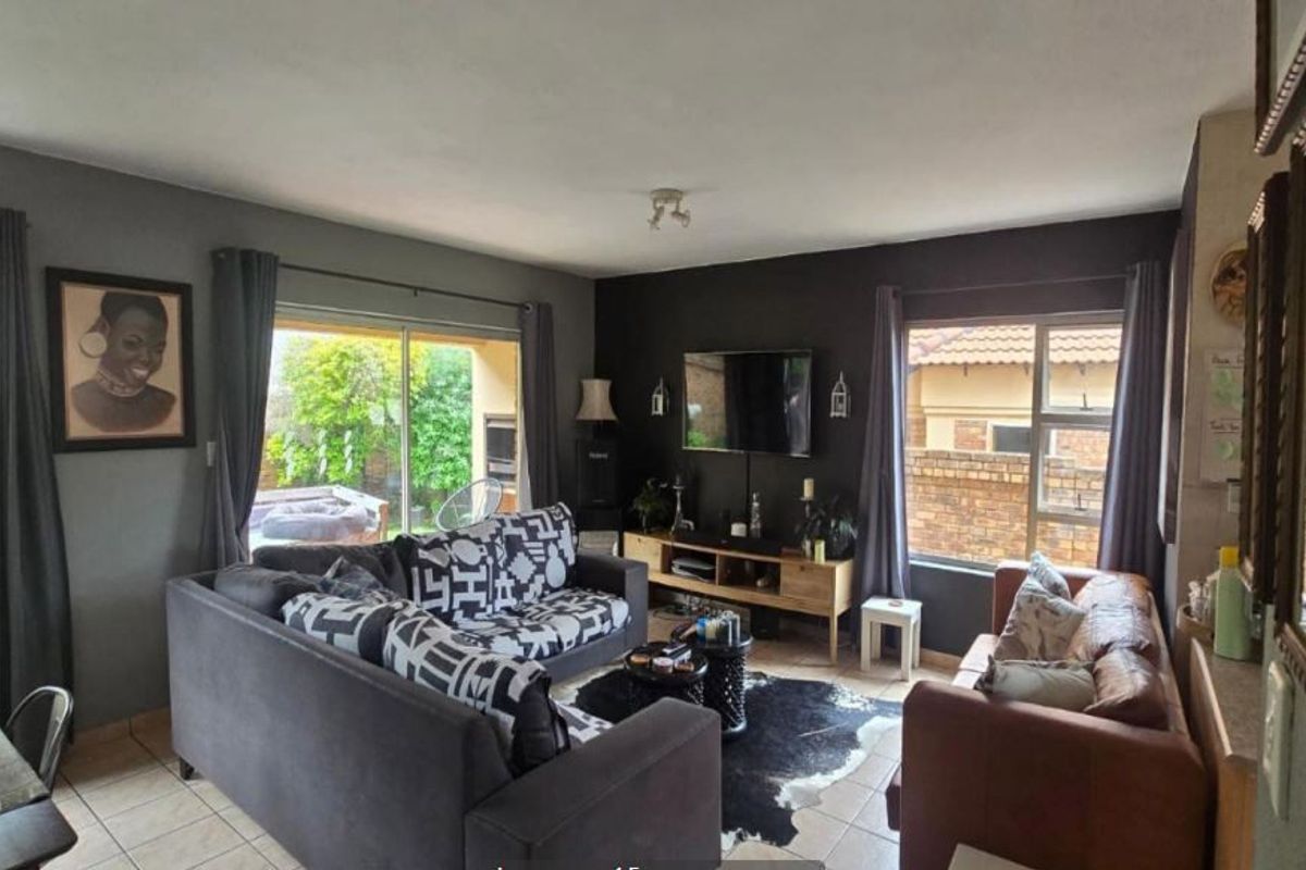 A comfortable living room featuring tiled flooring, large windows, and a sliding glass door providing access to the outdoor area.