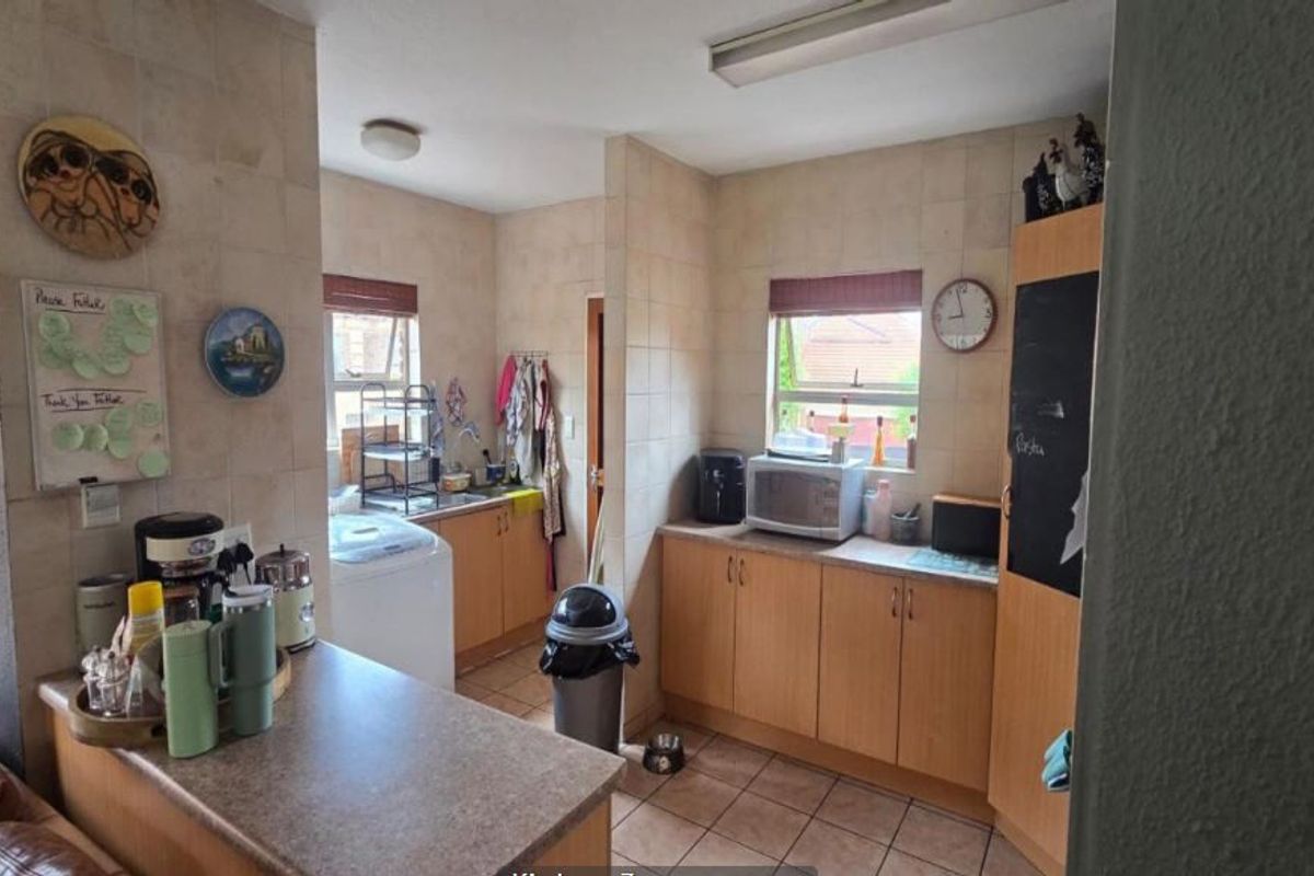 A functional kitchen featuring tiled walls, laminate countertops, and built-in cabinetry with a dedicated laundry area and sink.