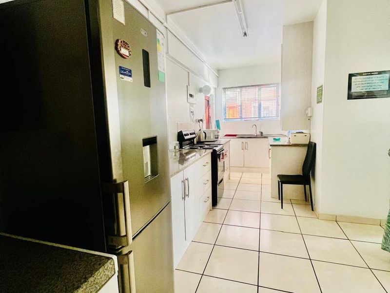 A functional kitchen featuring white cabinetry, laminate countertops, a stainless steel stove, and tiled flooring, offering a clean and practical workspace.