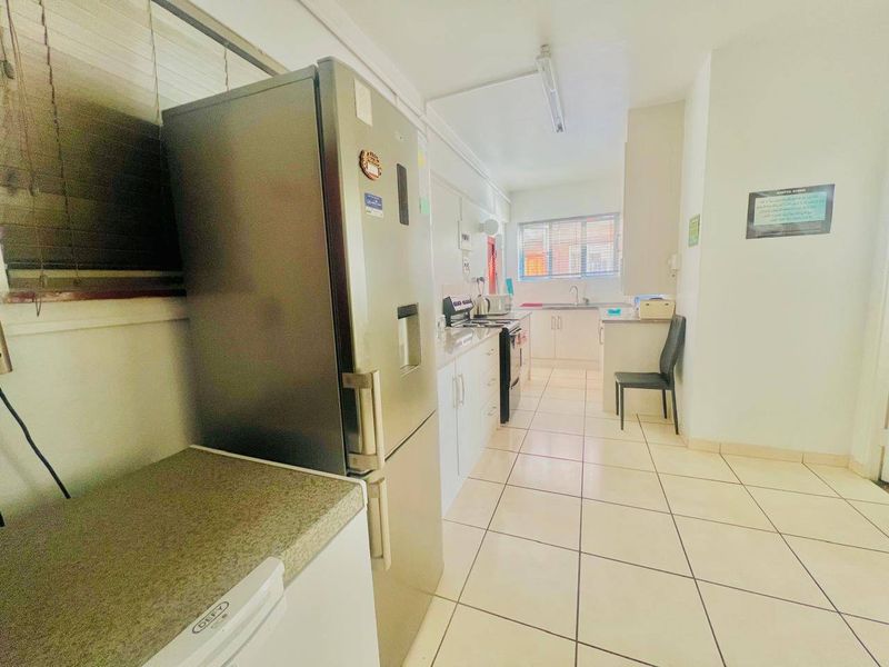 A functional kitchen featuring white cabinetry, stone countertops, a stainless steel sink, and tiled flooring, providing a practical workspace for daily cooking.