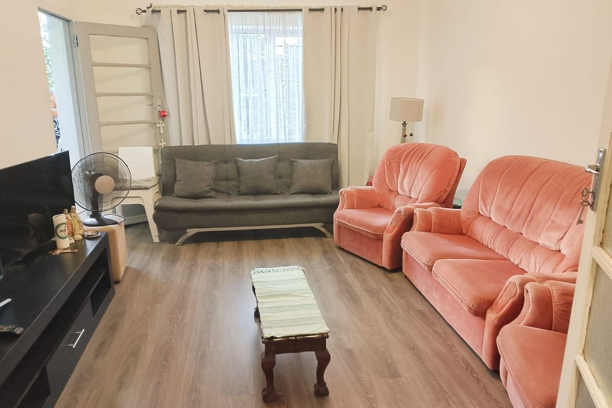 A living room featuring laminate flooring and a wall-mounted air vent, providing a functional and well-lit space.