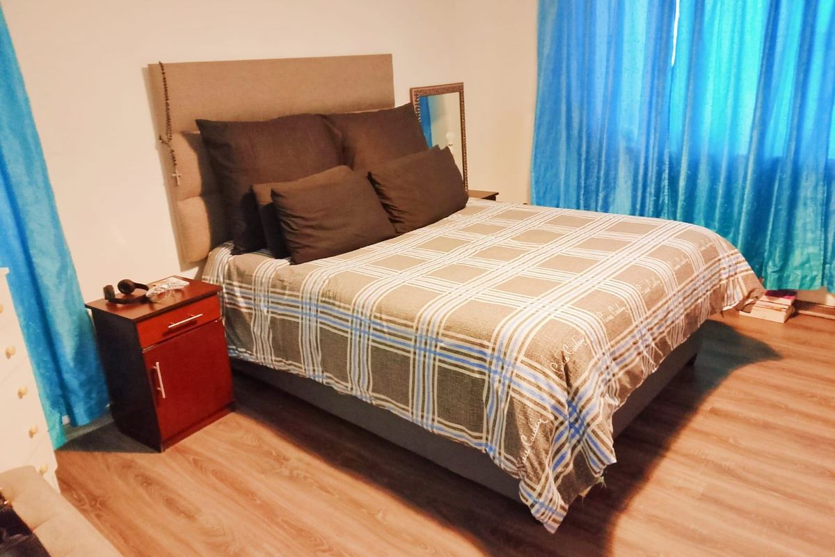 A bedroom featuring laminate flooring and neutral wall finishes, providing a functional space for rest.