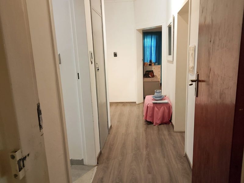 A functional hallway featuring laminate flooring and built-in storage cupboards, providing access to various rooms within the apartment.
