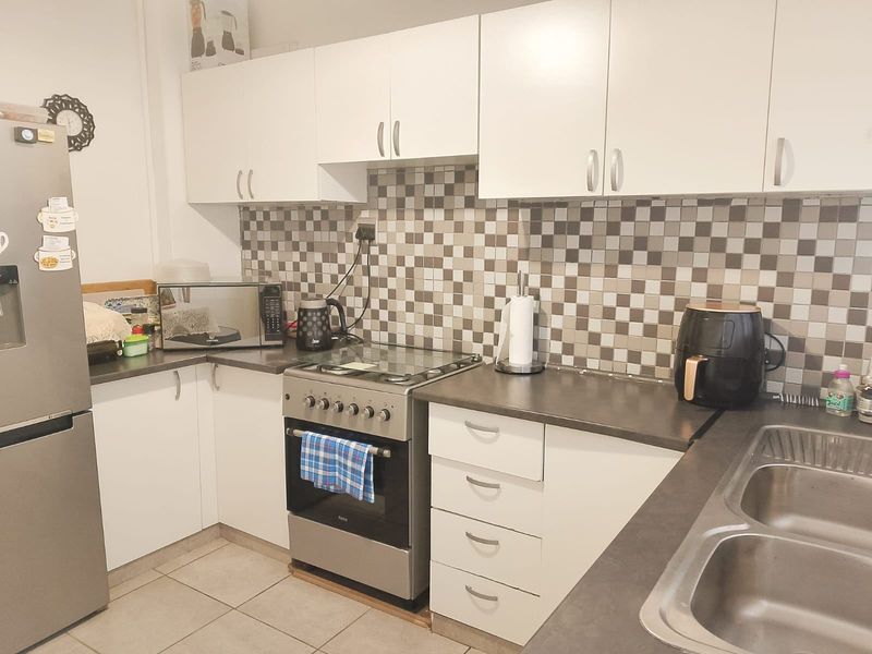 Functional kitchen featuring white cabinetry, mosaic tile backsplash, stainless steel stove, and double bowl sink with durable laminate countertops.