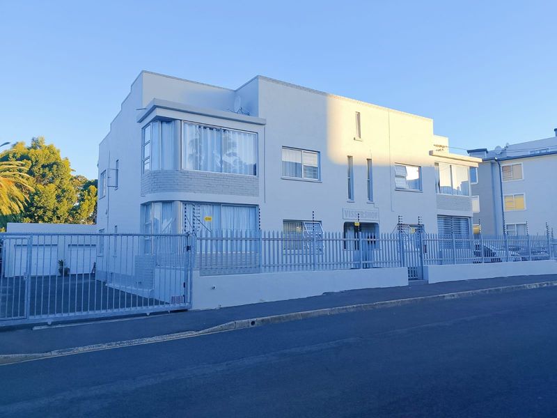 Street-facing view of the Vissershof apartment building, featuring a secure perimeter fence, electric security wiring, and a clean, well-maintained masonry facade.