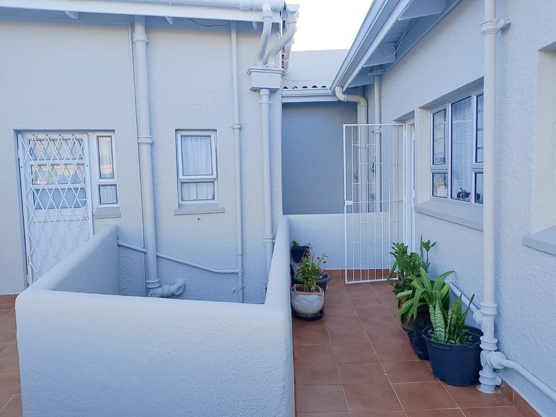 A clean, tiled outdoor balcony or walkway area featuring security gates and external building infrastructure.