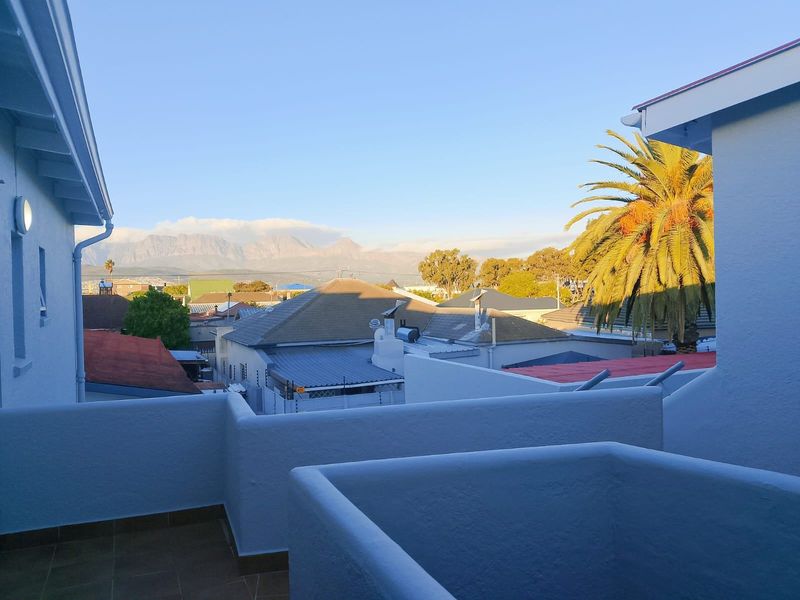 An elevated view from a balcony overlooking the surrounding neighborhood and distant mountain range.