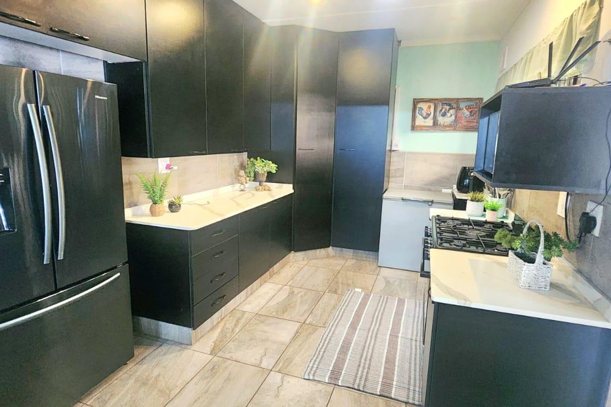 Modern kitchen featuring dark cabinetry, stone countertops, gas hob, and tiled flooring, offering a functional and contemporary cooking space.