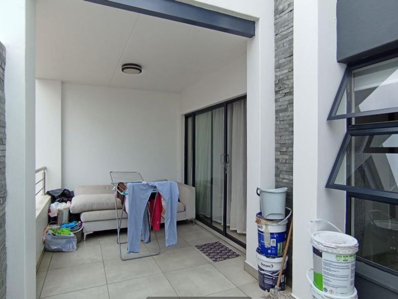 A covered patio area featuring modern stone cladding, tiled flooring, and large sliding glass doors providing access to the interior.
