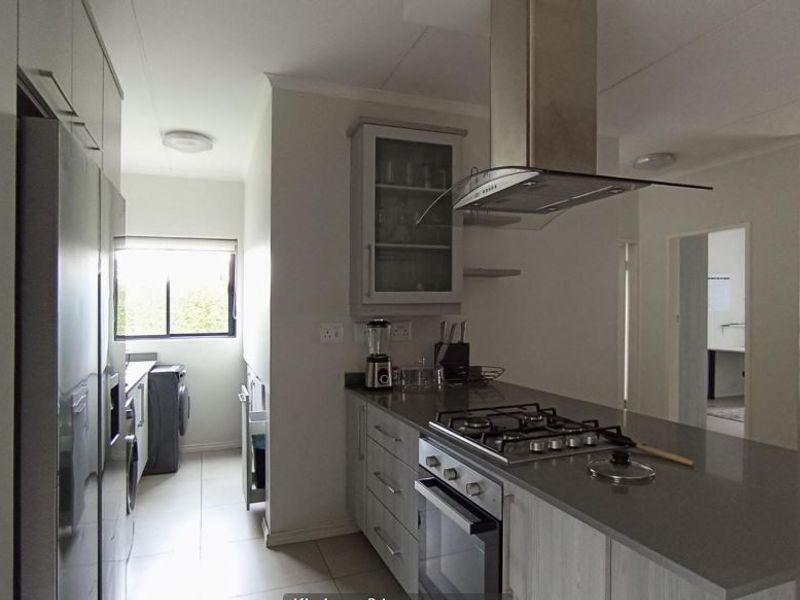 Modern kitchen featuring stone countertops, gas hob, built-in oven, extractor fan, and ample cabinetry, with an adjacent scullery area.