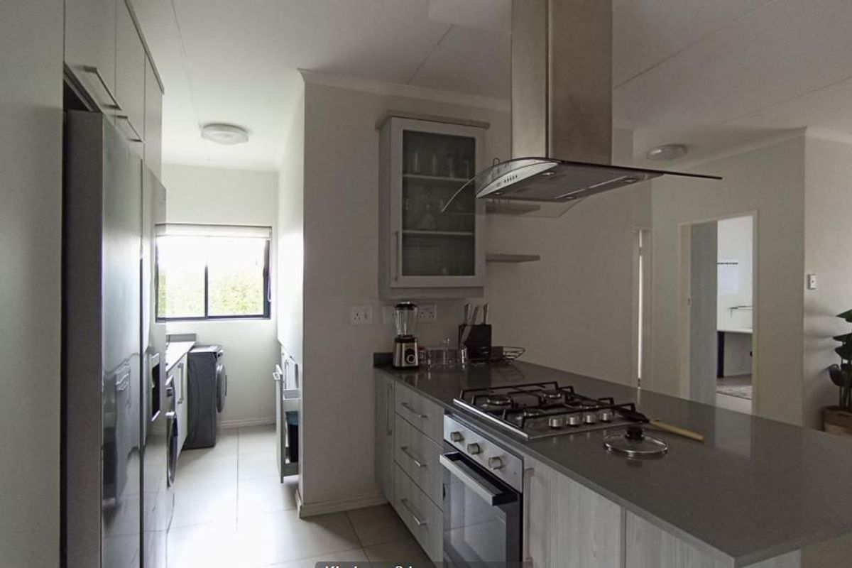 Modern kitchen featuring stone countertops, gas hob, built-in oven, extractor fan, and ample cabinetry, with an adjacent scullery area.