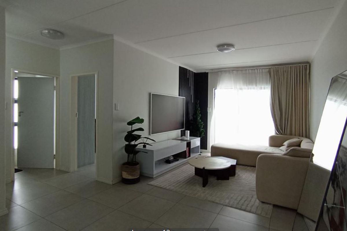 A bright and modern living room featuring tiled floors, a decorative slat feature wall, and large sliding glass doors providing natural light.