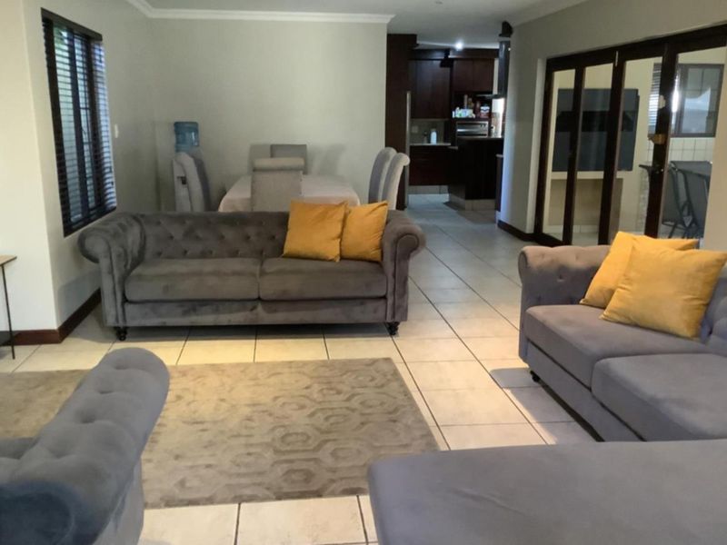 Spacious open-plan living and dining area featuring tiled flooring, neutral walls, and direct access to an adjacent kitchen space.