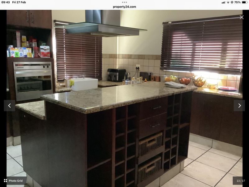 A functional kitchen featuring dark wood cabinetry, granite countertops, a central island with built-in wine storage, and a stainless steel extractor fan.