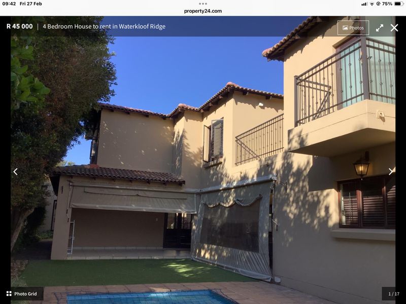 Rear view of the property featuring a covered patio area, balcony with wrought iron railings, swimming pool, and artificial lawn.