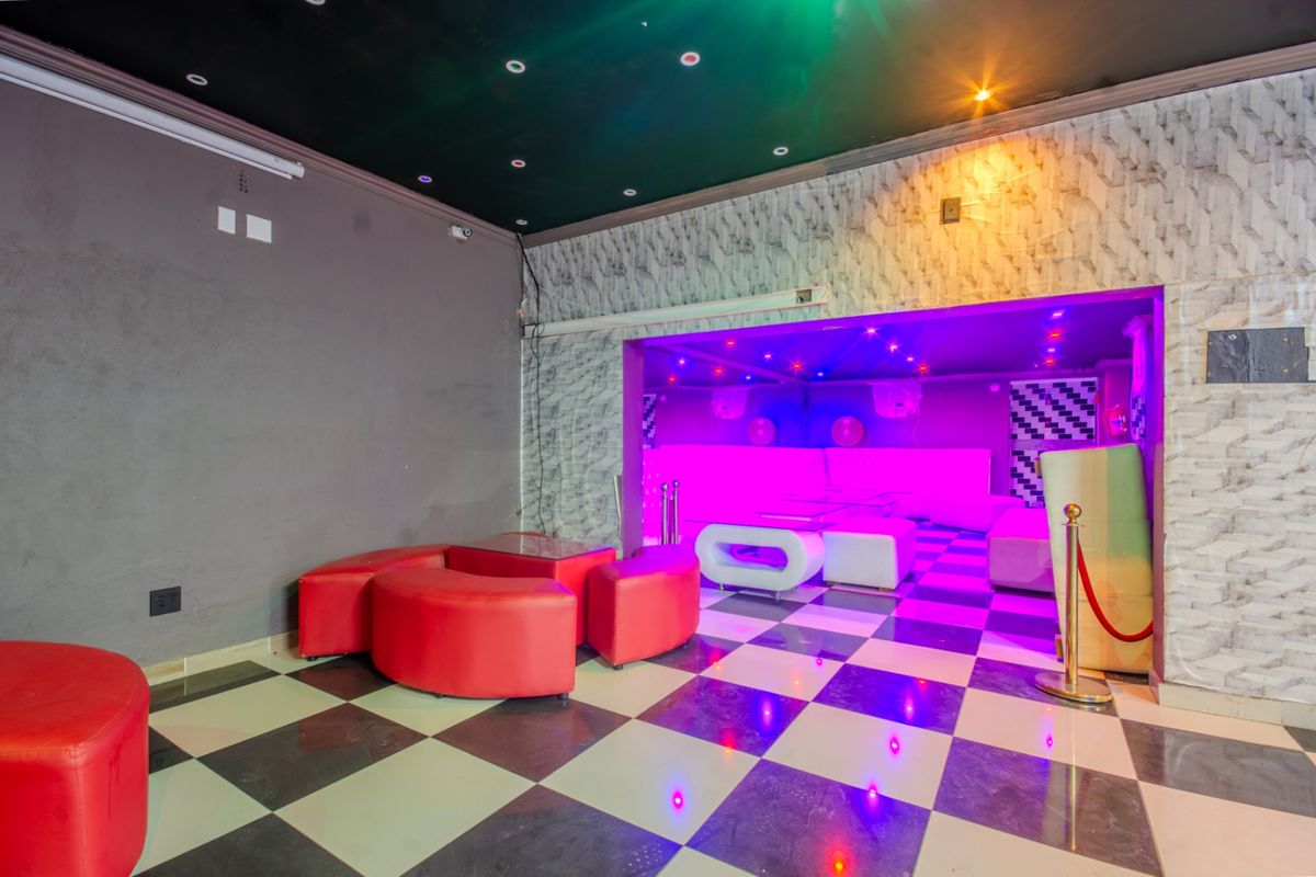A commercial lounge or club area featuring checkered flooring, textured wall finishes, and integrated ambient lighting, suitable for entertainment or hospitality use.