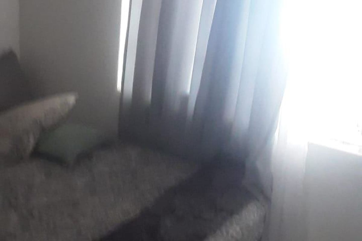 A bedroom featuring tiled flooring and a window with curtains, providing natural light to the space.