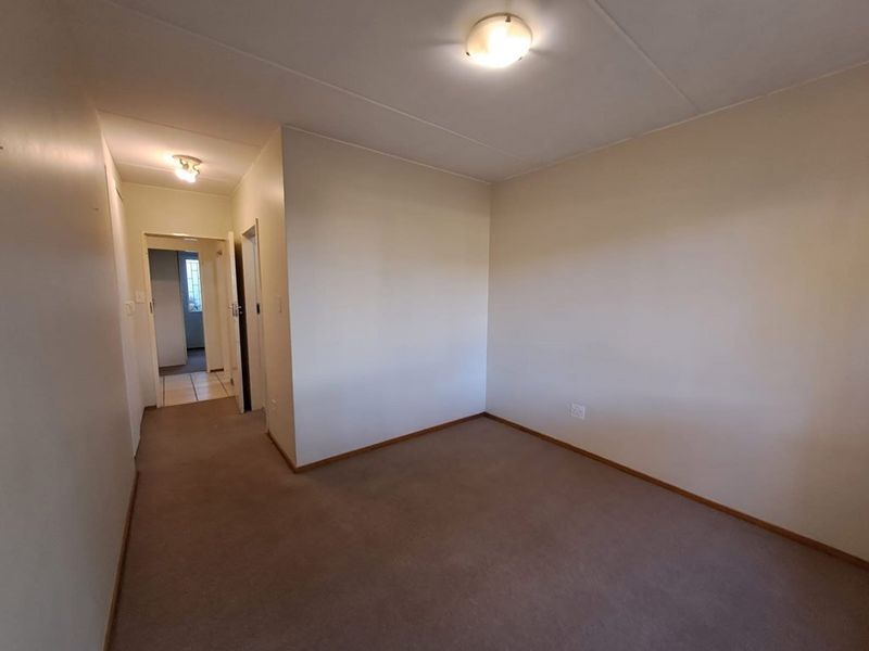 An empty bedroom featuring neutral walls, carpet flooring, and flush mount ceiling lighting, providing a blank canvas for personalization.