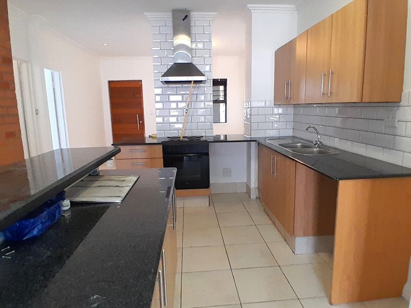 A functional kitchen featuring wooden cabinetry, granite countertops, a subway tile backsplash, and a built-in oven with a stainless steel extractor fan.