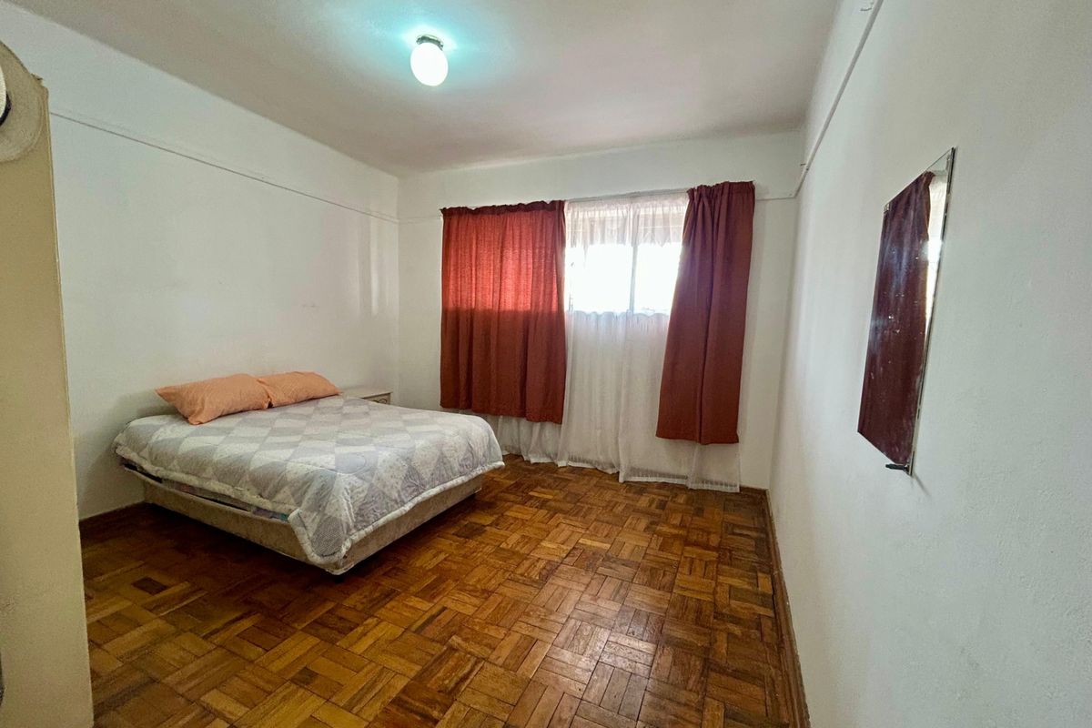 A bedroom featuring original parquet flooring and a simple ceiling light fixture, offering a blank canvas for renovation and modernization.