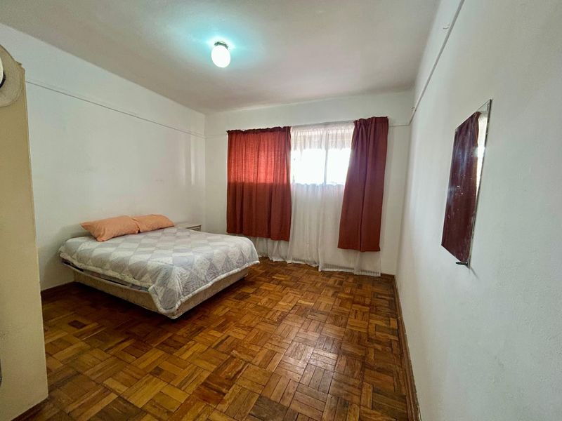 A bedroom featuring original parquet flooring and a simple ceiling light fixture, offering a blank canvas for renovation and modernization.
