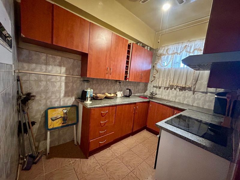 A functional kitchen featuring laminate cabinetry, granite countertops, a ceramic tile backsplash, and an integrated electric hob with an extractor fan.