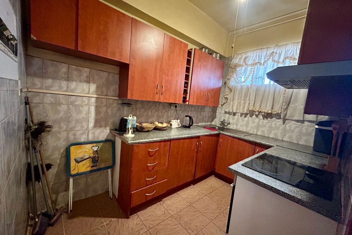 A functional kitchen featuring laminate cabinetry, granite countertops, a ceramic tile backsplash, and an integrated electric hob with an extractor fan.