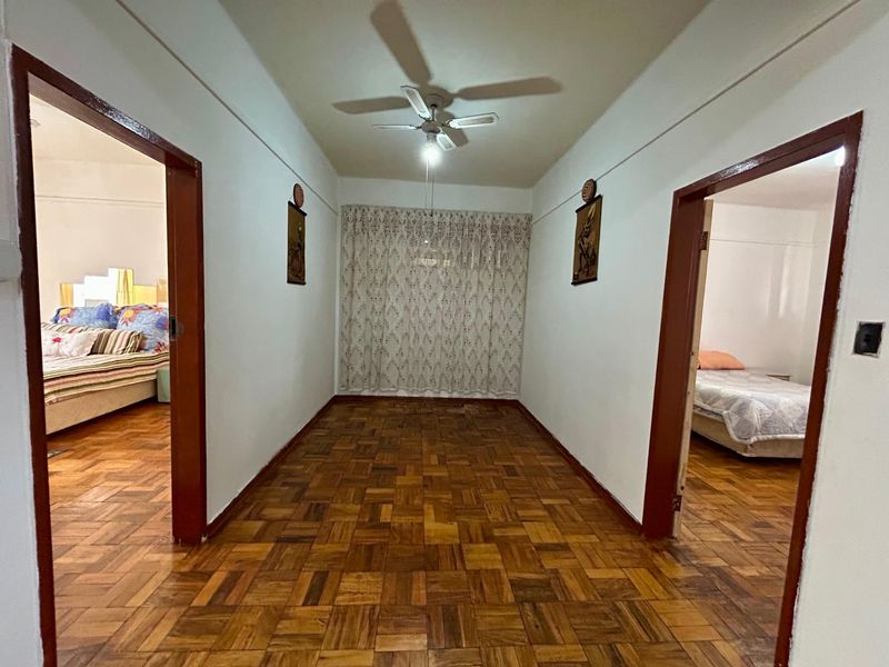 A spacious hallway featuring classic parquet flooring and timber door frames, providing access to adjacent bedrooms.