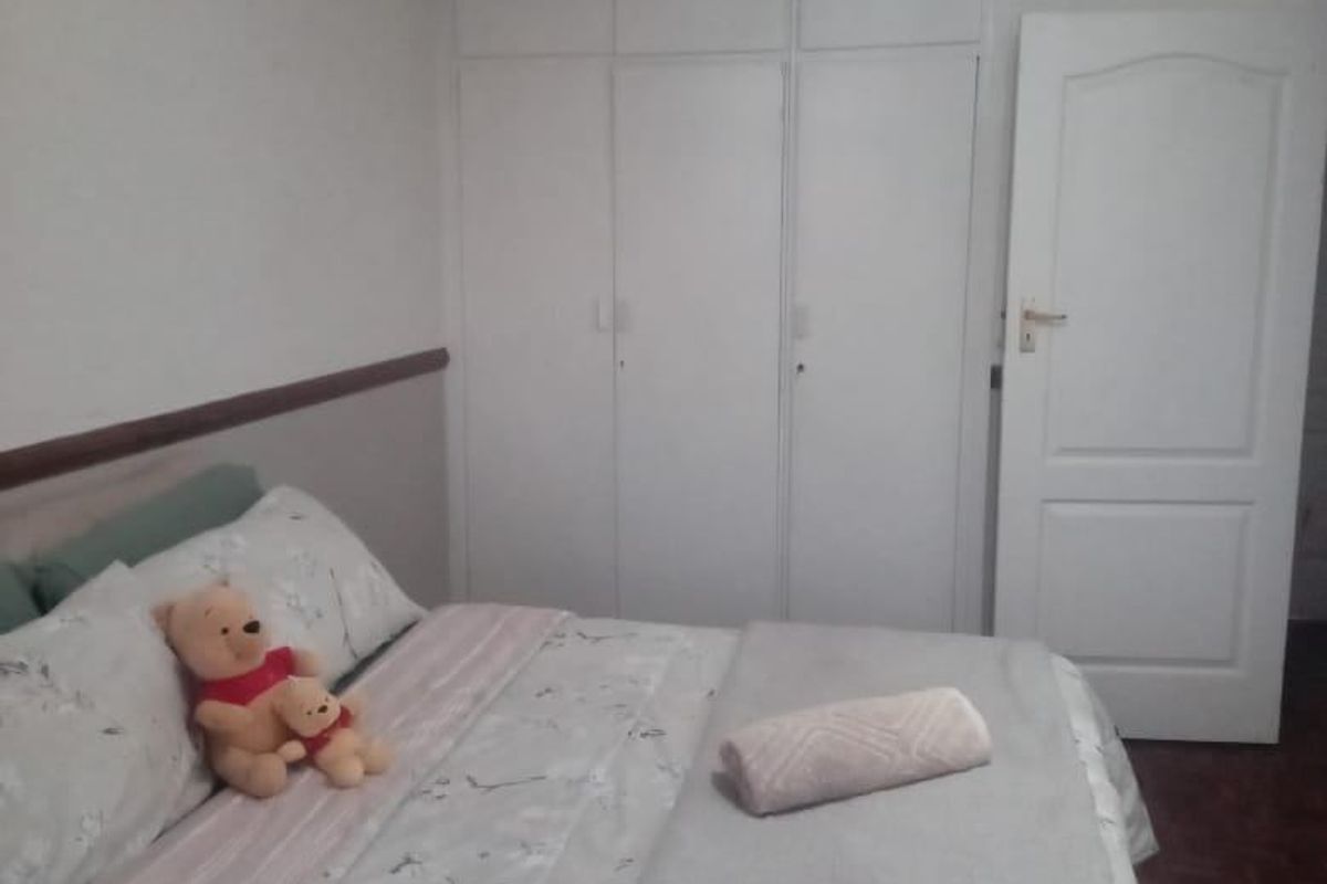 A bedroom featuring built-in white cupboards, a ceiling fan, and parquet flooring.