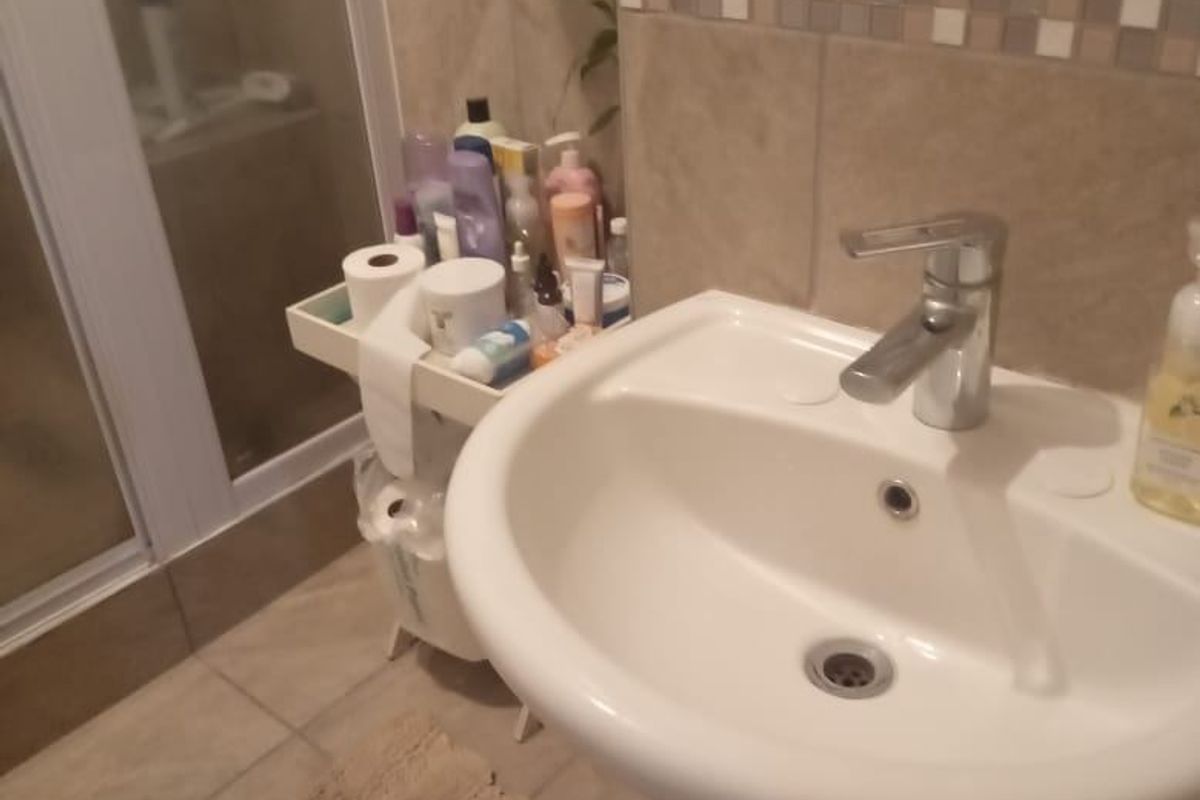 A functional bathroom featuring a pedestal basin with a chrome mixer tap and a separate shower enclosure with tiled finishes.