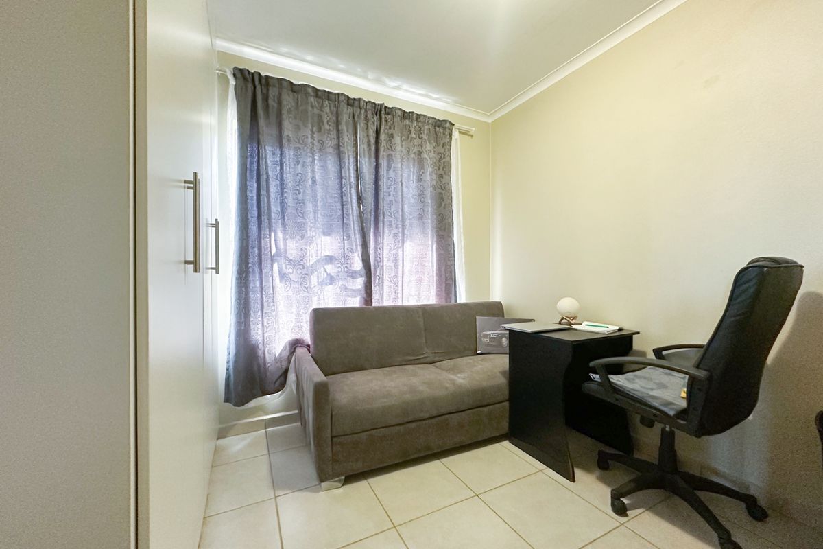 A compact bedroom featuring tiled flooring, a built-in wardrobe, and neutral wall finishes, suitable for use as a guest room or home office.