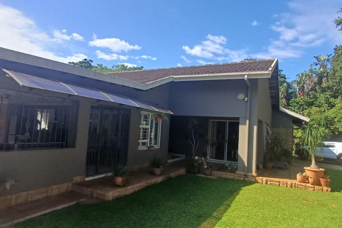 Rear view of the house featuring a paved patio area, sliding door access, and a well-maintained garden.