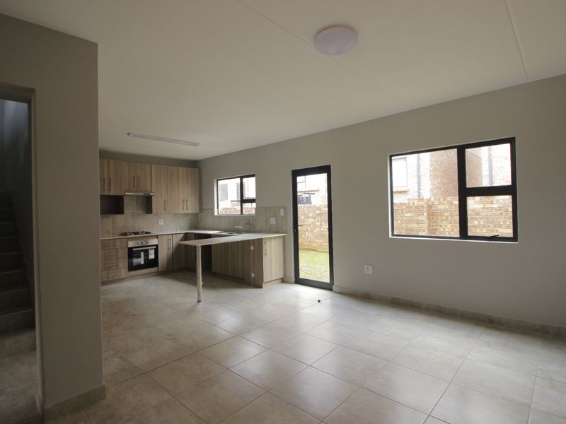 Spacious open-plan kitchen and living area featuring modern cabinetry, built-in appliances, tiled flooring, and direct access to the rear garden.