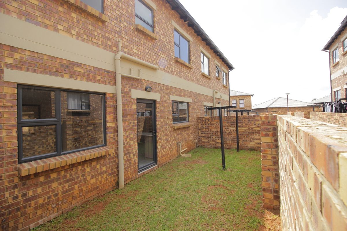 A private rear garden area featuring face brick exterior walls, aluminium window frames, and a dedicated washing line space.