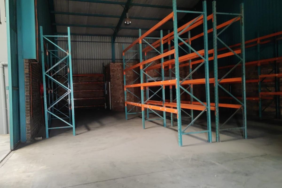 Spacious industrial utility area featuring durable concrete flooring, exposed brick walls, and heavy-duty steel racking systems suitable for storage or warehouse operations.