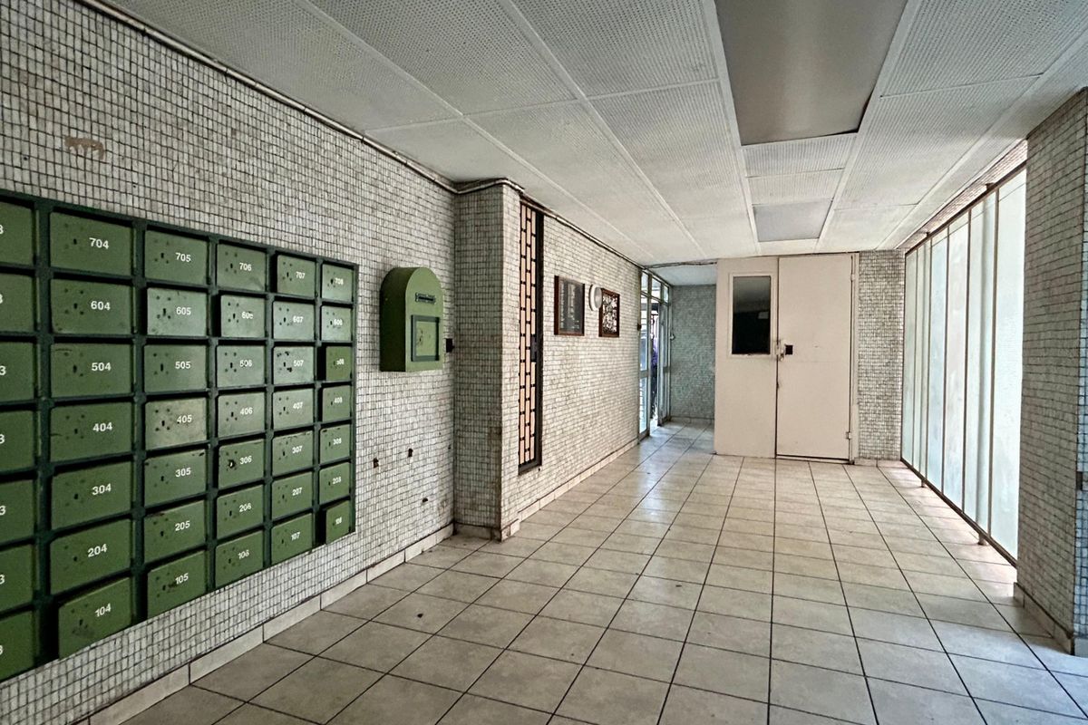 A communal apartment building entrance lobby featuring tiled flooring, mosaic wall tiling, and a bank of built-in mailboxes.