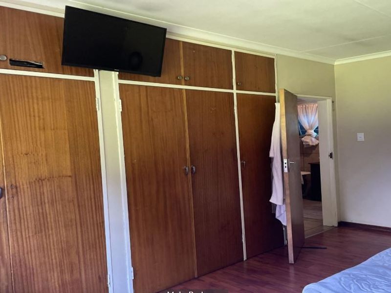 Bedroom featuring extensive built-in wooden cabinetry, laminate flooring, and direct access to an adjoining room.