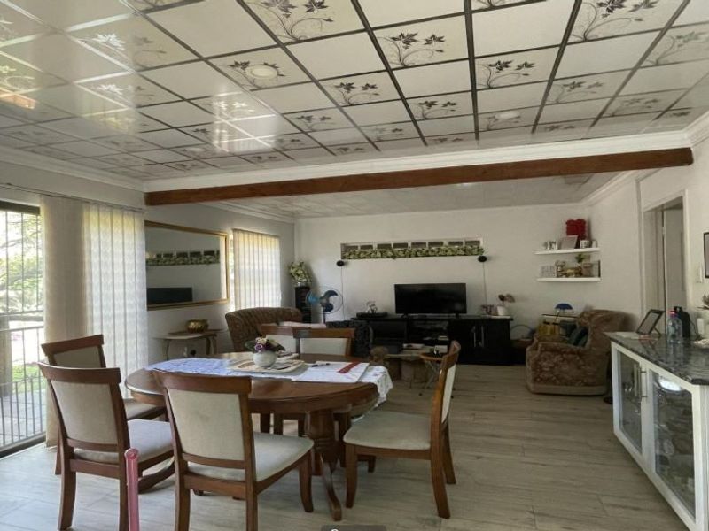 Open plan living and dining area featuring a stone-topped kitchen counter, decorative ceiling tiles, and sliding glass doors leading to an outdoor space.