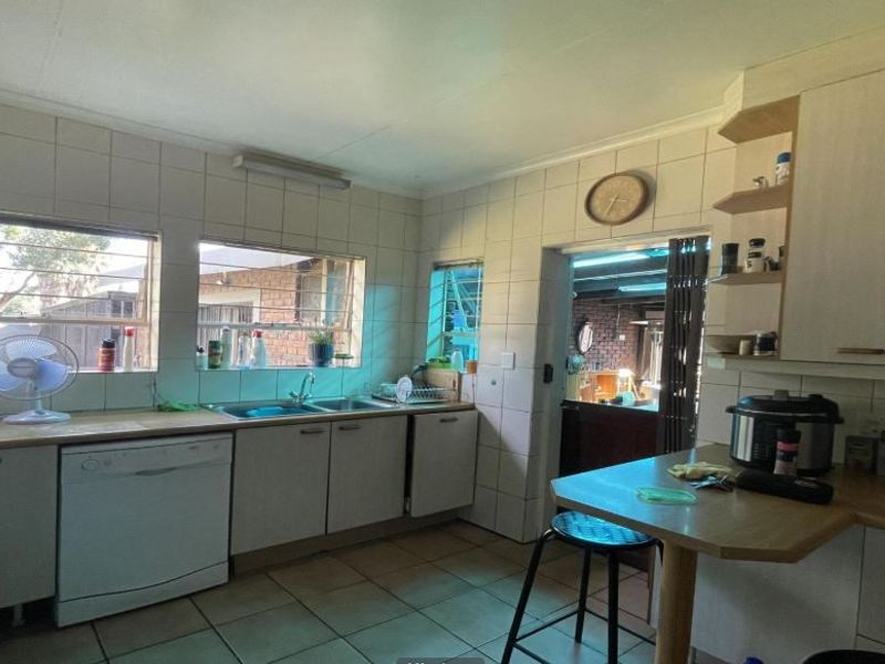 Functional kitchen featuring tiled splashbacks, laminate countertops, built-in cabinetry, and a breakfast bar area with direct access to an adjacent living space.