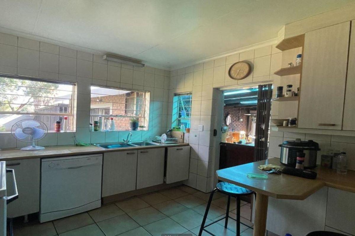 Functional kitchen featuring tiled splashbacks, laminate countertops, built-in cabinetry, and a breakfast bar area with direct access to an adjacent living space.