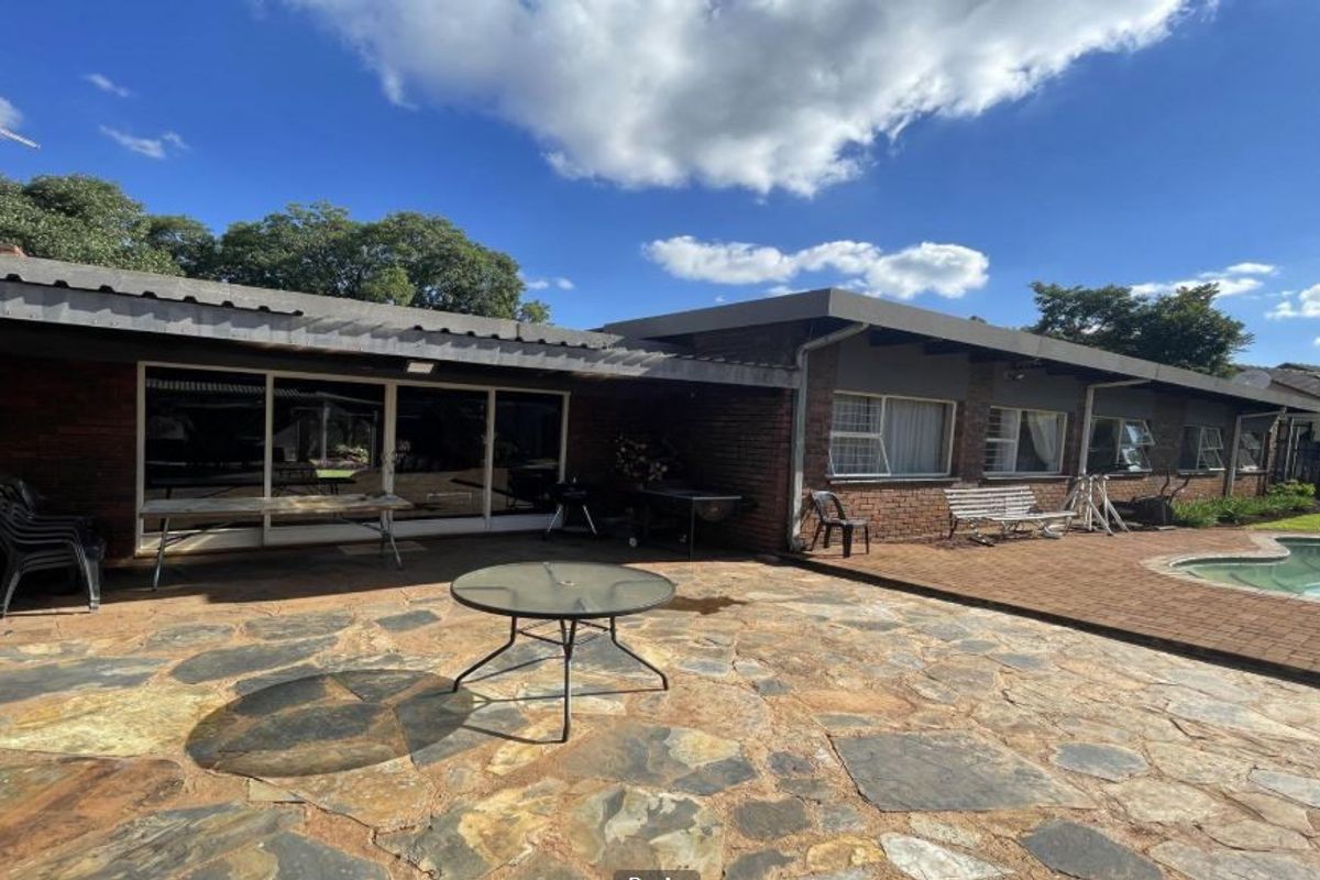 Spacious rear exterior featuring a paved patio area, covered veranda, and a swimming pool, ideal for outdoor entertaining.