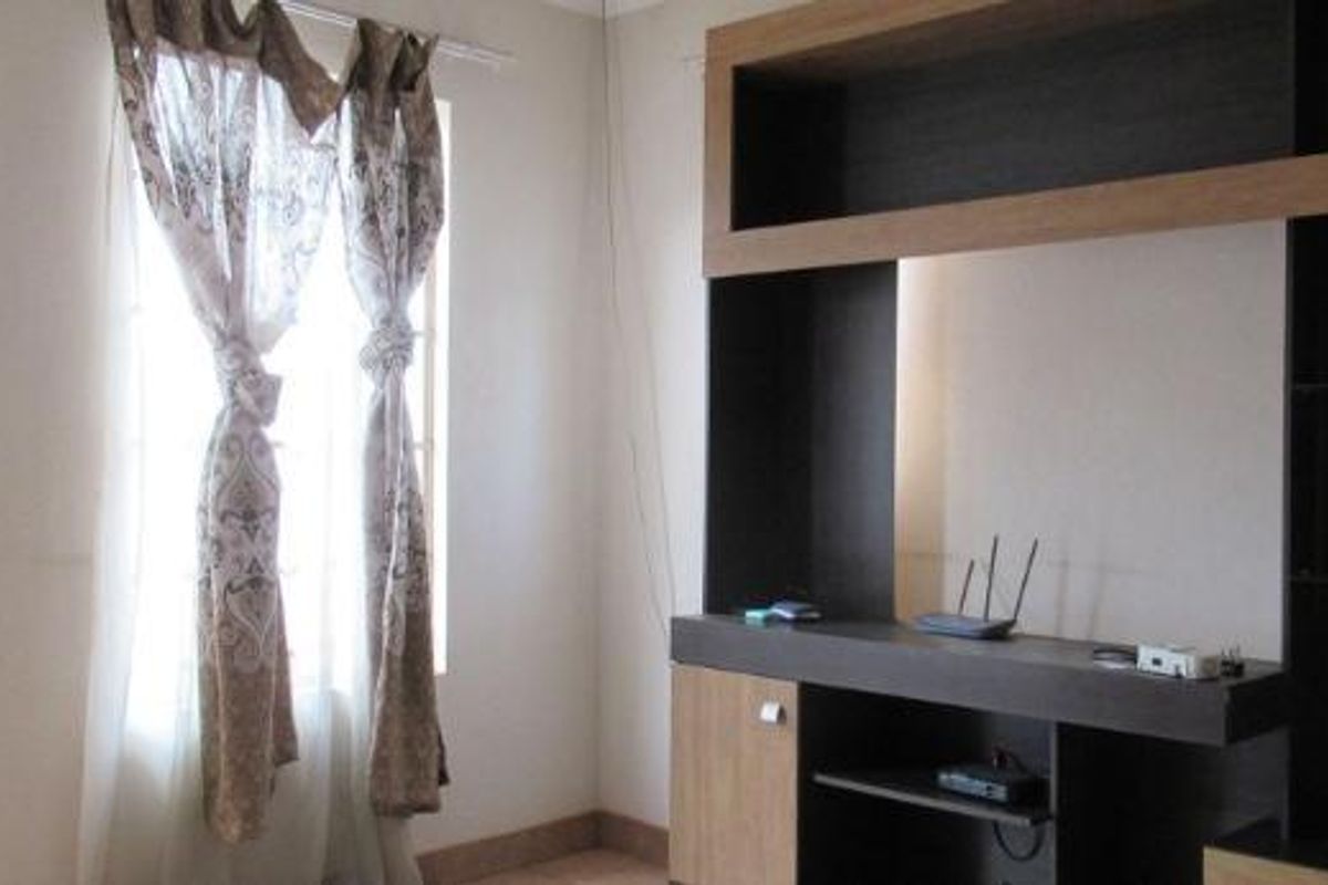 A living room featuring a large built-in dark wood media console and a window with curtains.