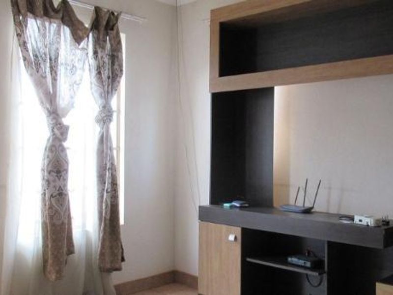 A living room featuring a large built-in dark wood media console and a window with curtains.
