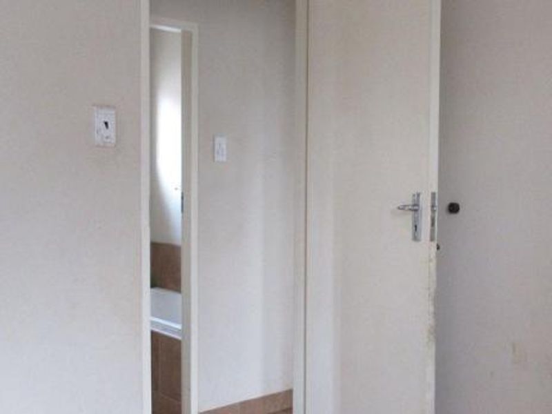 A view of an interior hallway featuring a standard internal door and access to an adjacent room.