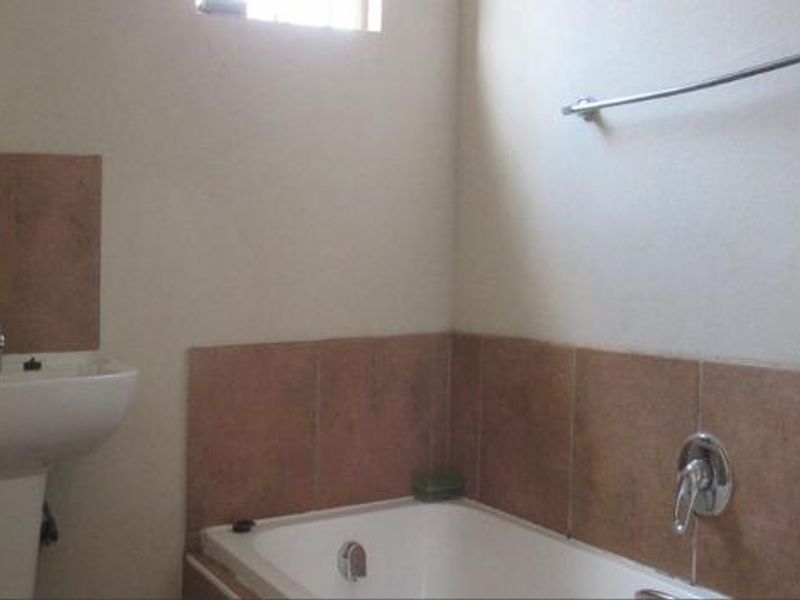 A functional bathroom featuring a pedestal basin, a bathtub with tiled splashbacks, and a wall-mounted towel rail.
